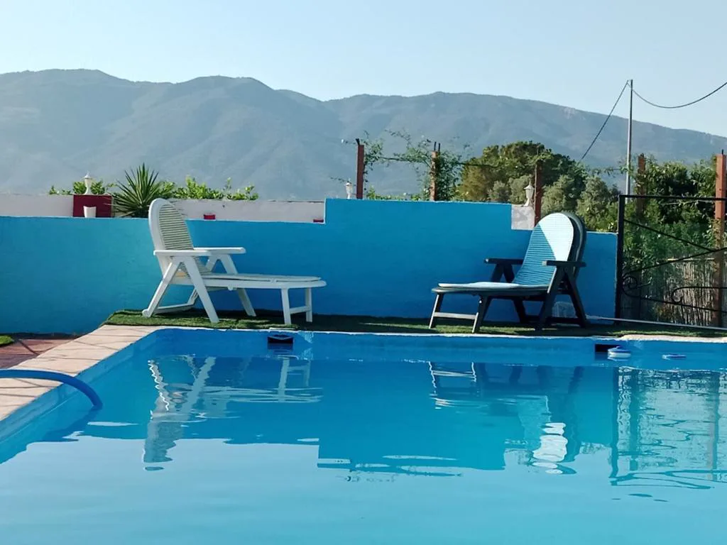 Piscina azul con muros blancos y montañas al fondo