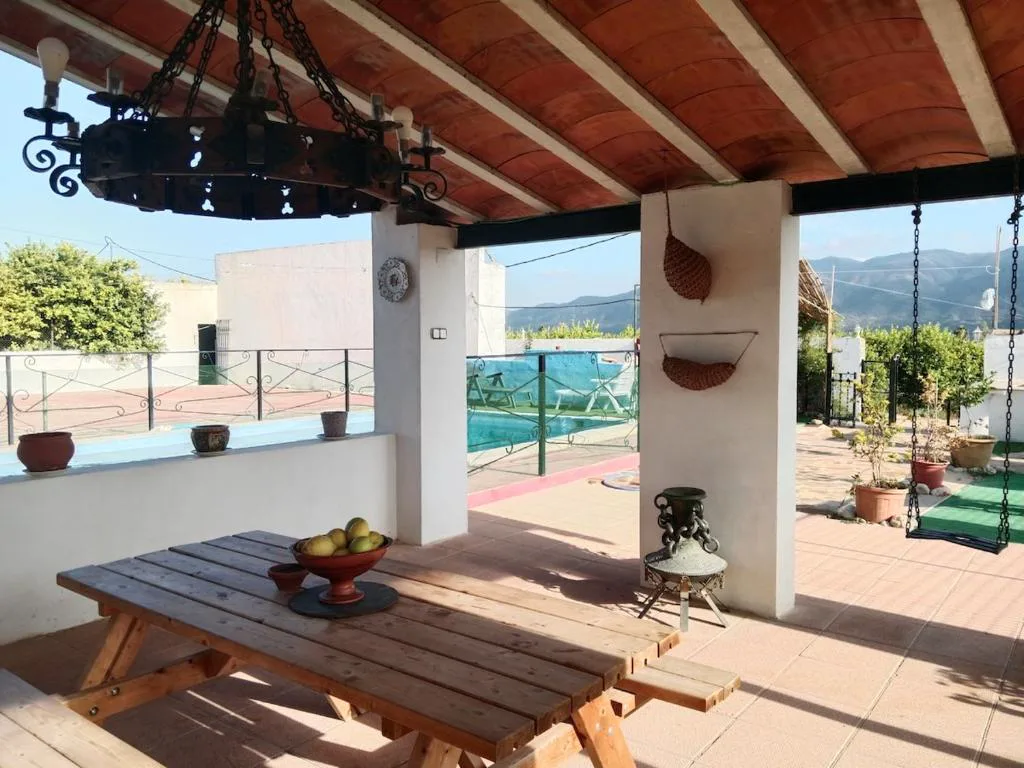 Porche con mesa de madera y vistas a la piscina