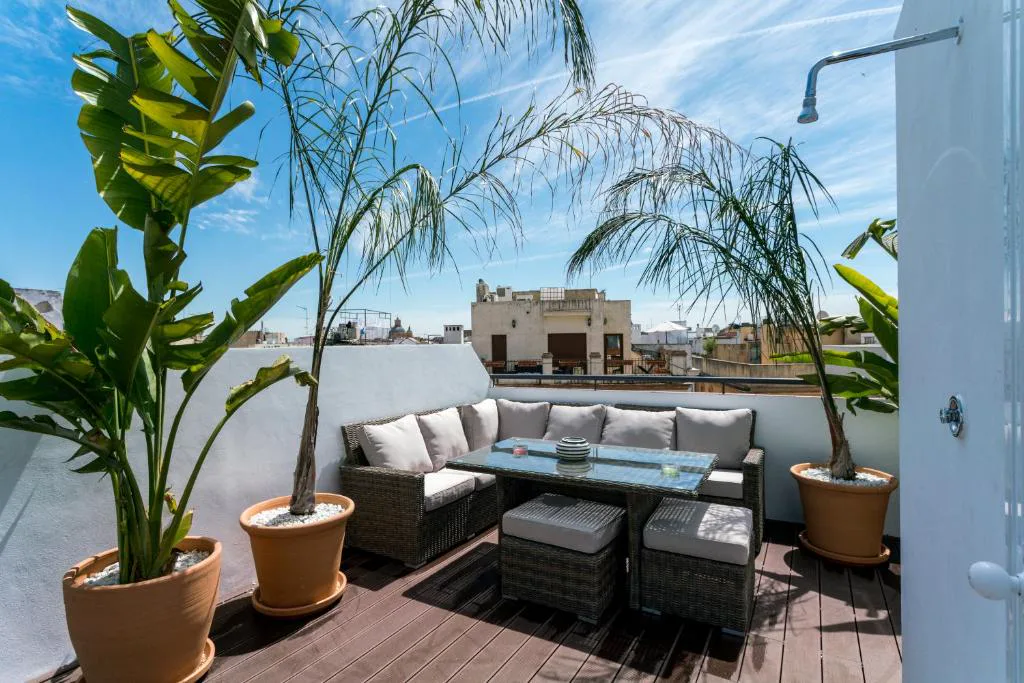 Terraza con sofás de exterior, plantas y palmeras