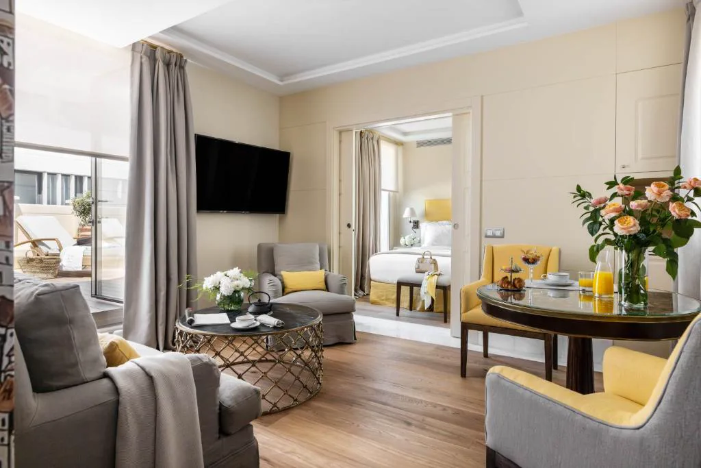 Suite con salón, cama y balcón en tonos crema y amarillo