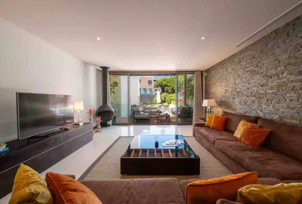 Salón con chimenea y pared de piedra en la villa de Vale do Lobo