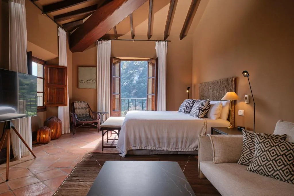 Dormitorio con vigas de madera vista y balcón a la montaña, Valldemossa Hotel