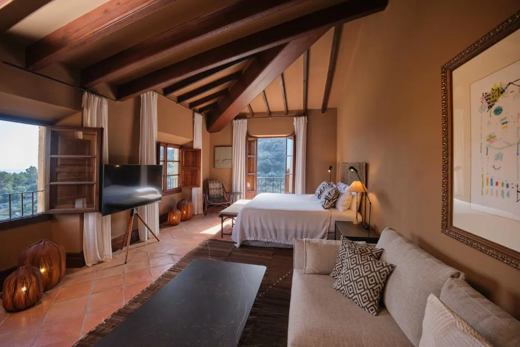 Dormitorio en tonos tierra con sofá y vistas a la montaña, Valldemossa Hotel