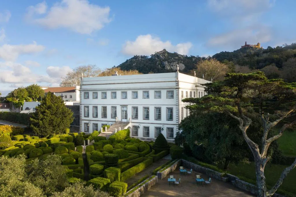 Fachada del Palácio de Seteais con el Palacio da Pena asomando entre los árboles de la Sierra de Sintra