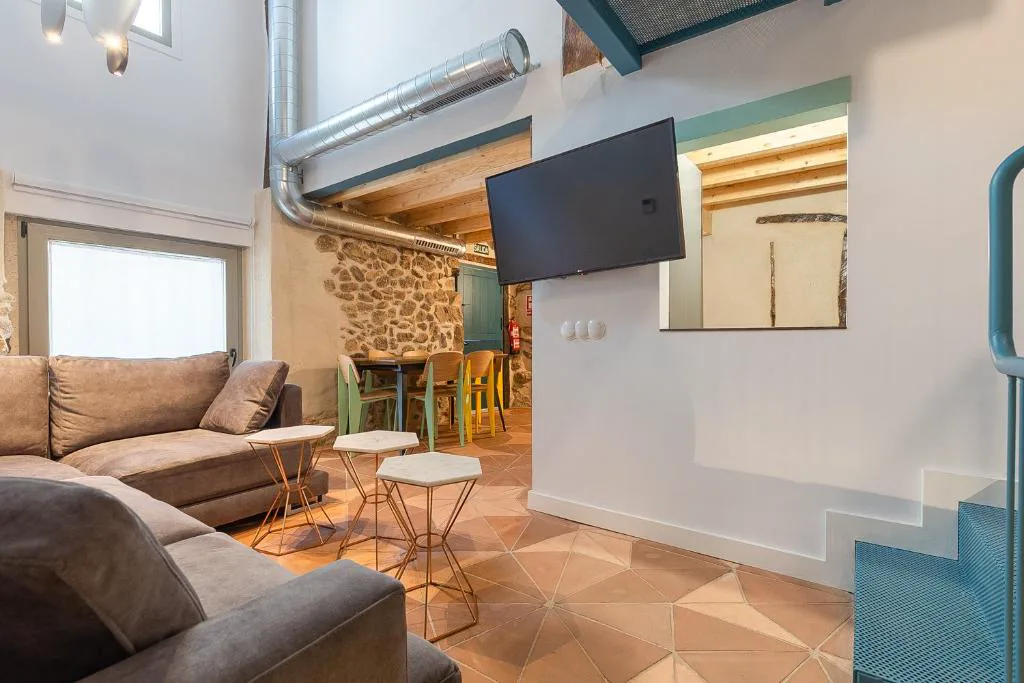 Salón con sofá gris y televisión en una casa de piedra