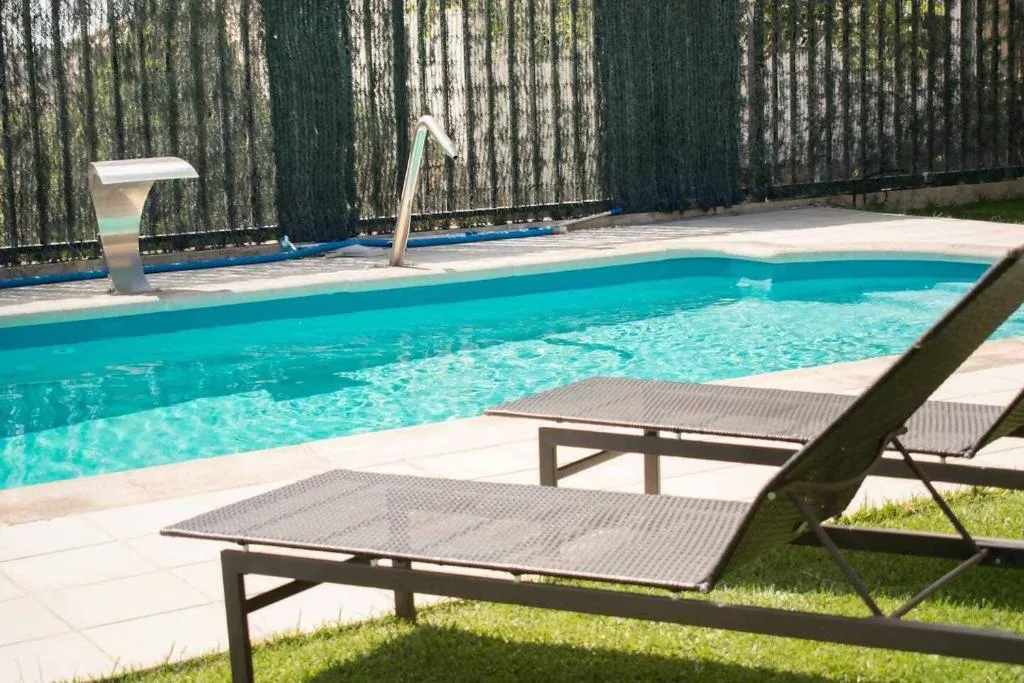 Piscina con tumbonas y vegetación alrededor