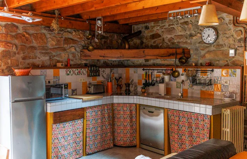 Cocina de piedra con azulejos de colores y vigas de madera