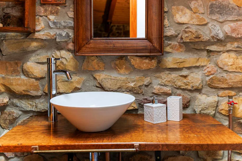 Lavabo de piedra con pila blanca y espejo de madera