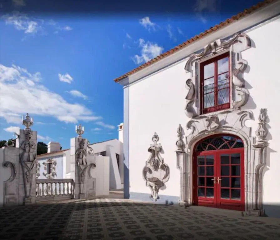 Entrada barroca con puerta roja y remates de piedra tallada, Vermelho Melides