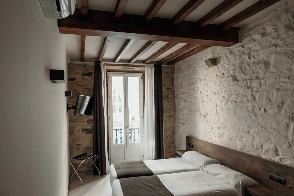Habitación con paredes de piedra vista, vigas de madera originales y balcón con vistas a la calle, Via Aetcal Hotel & Wellness
