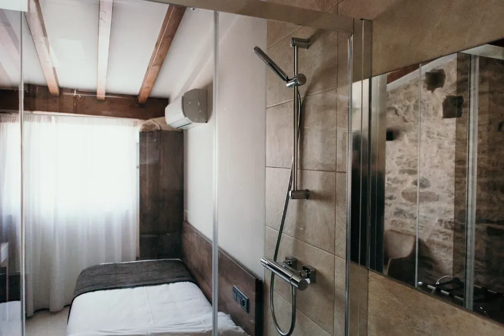 Ducha de obra con mampara de cristal y pared de piedra original, baño del Via Aetcal Hotel & Wellness en Santiago de Compostela