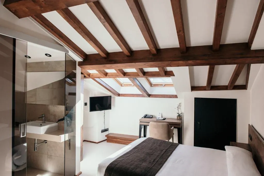 Habitación abuhardillada con vigas de madera y ventanas de tejado, Via Aetcal Hotel & Wellness en Santiago de Compostela