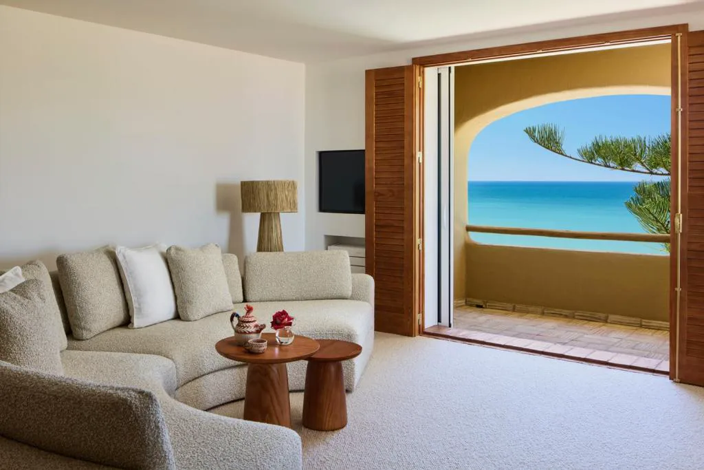 Salón con sofá curvo y balcón abierto al mar, Vila Joya
