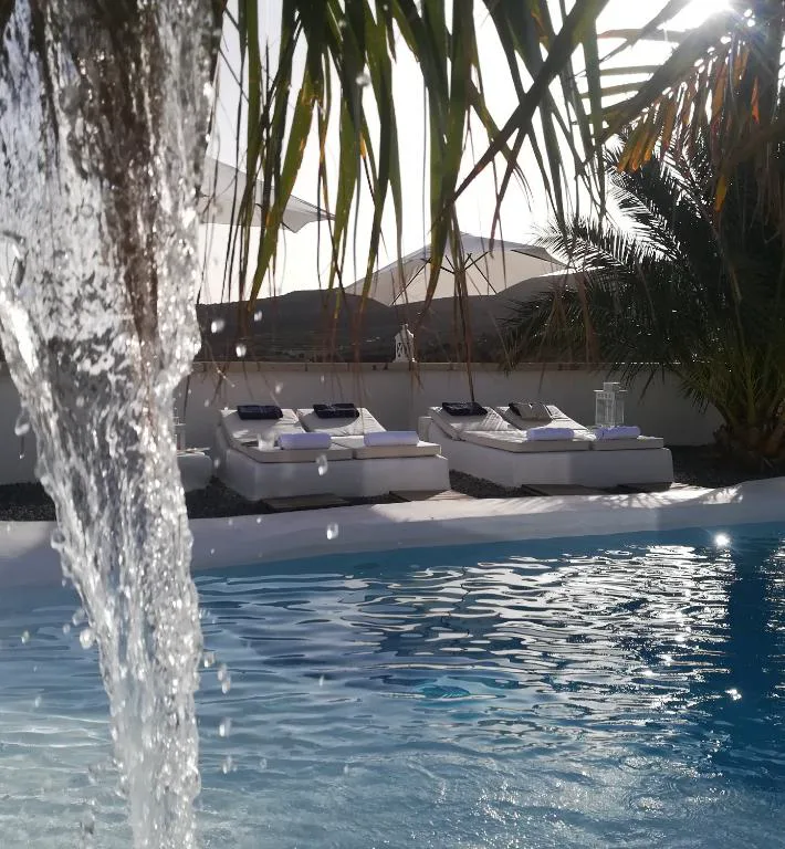 Cascada de agua sobre la piscina con tumbonas y vistas a la montaña, Villa Adriano
