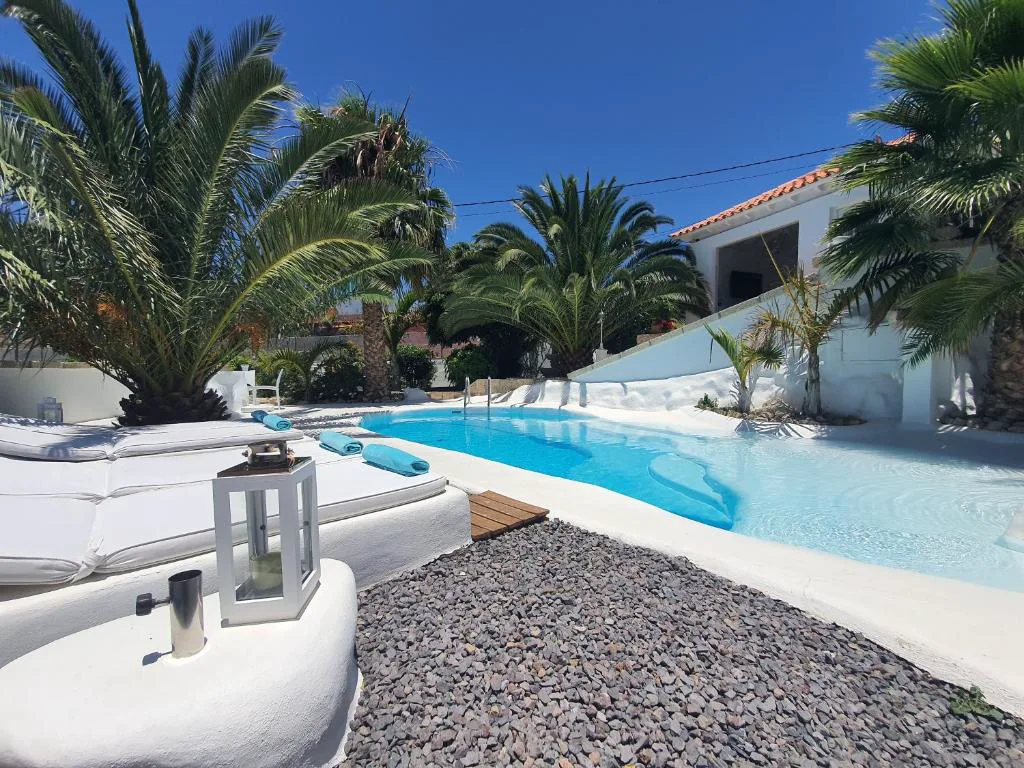 Piscina privada blanca de Villa Adriano rodeada de palmeras, con vistas a la montaña, en Sabina Alta, Arico