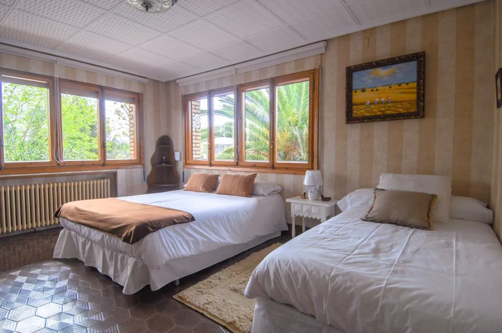 Dormitorio con dos camas y ventanas