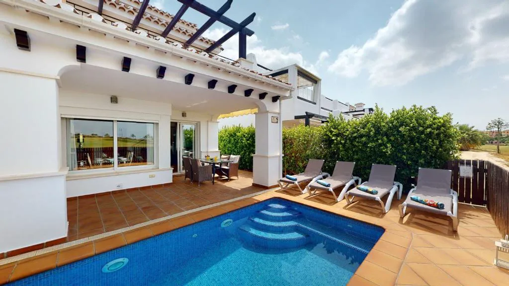 Piscina privada con tumbonas junto a una terraza cubierta