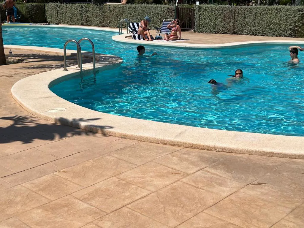 Piscina comunitaria con bordes de piedra y tumbonas