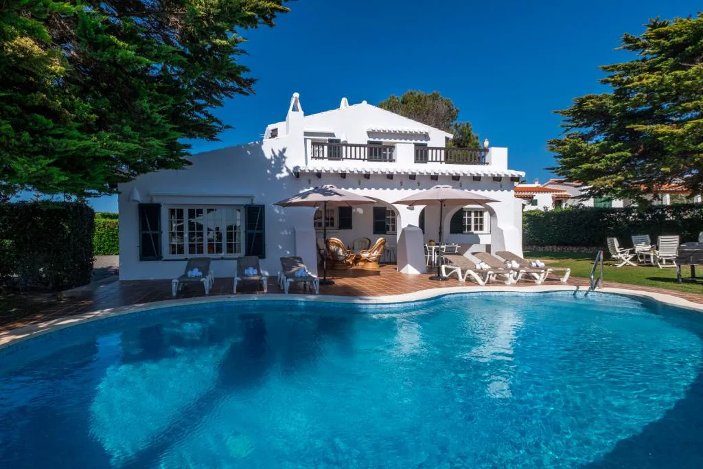 Piscina con tumbonas frente a la villa blanca de dos plantas, Villa Binigo
