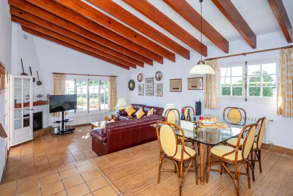 Salón con sofá de cuero y decoración marinera bajo techo de vigas de madera, Villa Binigo