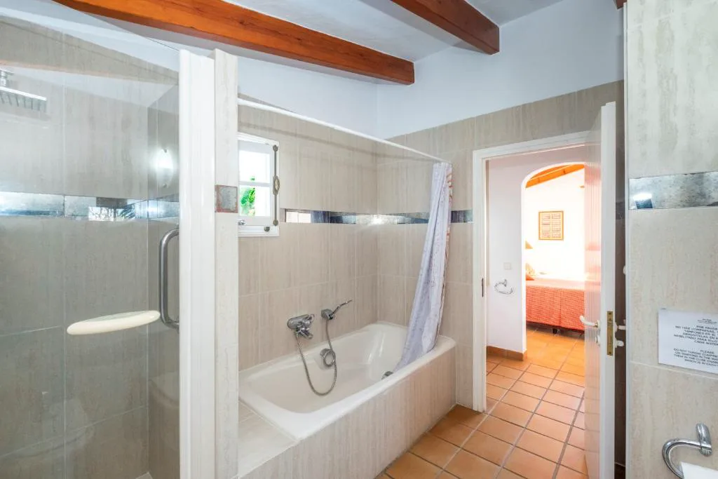 Baño con bañera y techo de vigas de madera vista, Villa Binigo