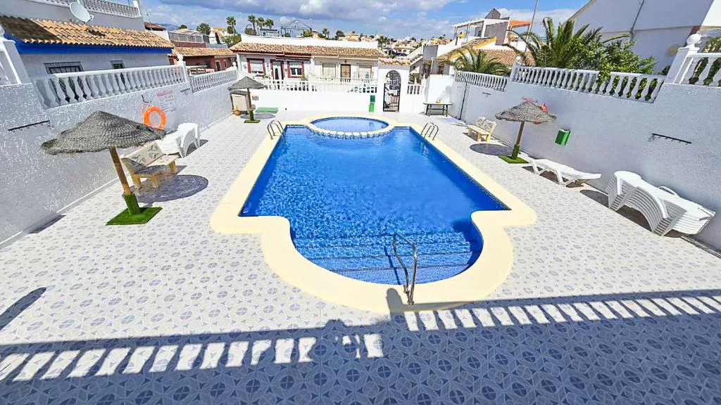 Piscina azul con tumbonas en un patio blanco