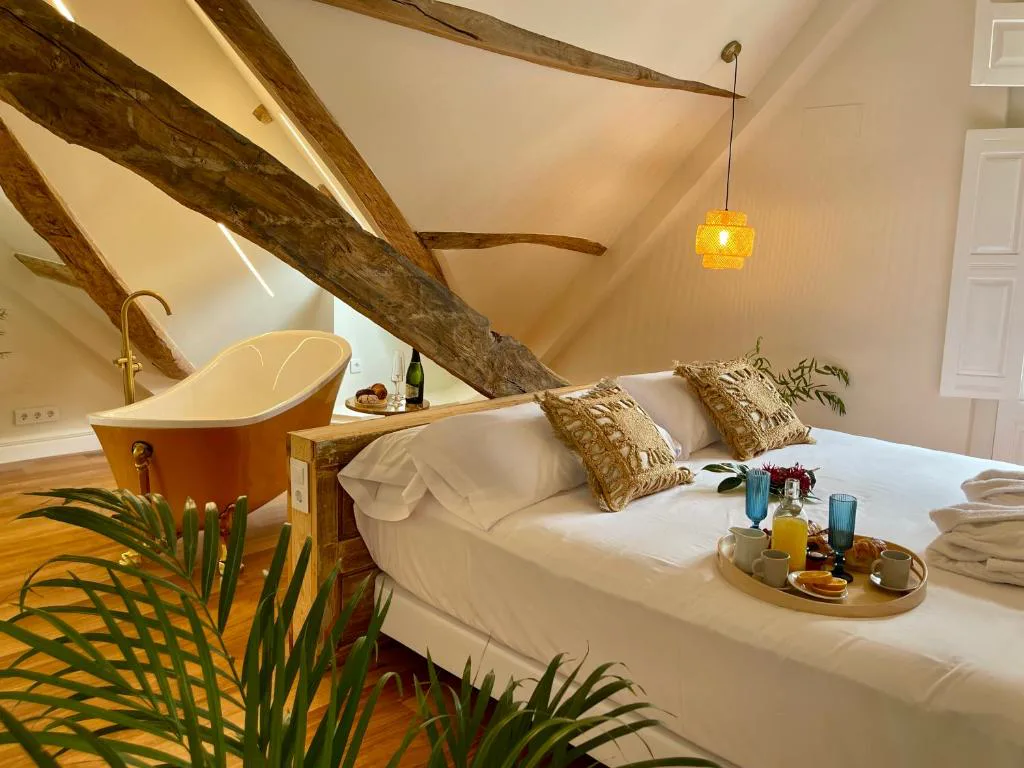 Bañera exenta de cobre junto a la cama, con bandeja de desayuno y vigas de madera vistas, Villa Boutique 1880