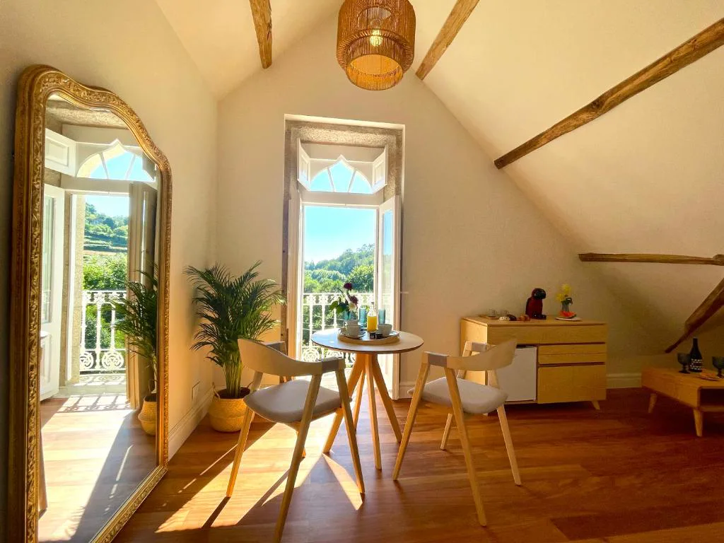 Rincón de estar con espejo dorado de época y puertas góticas abiertas al balcón, Villa Boutique 1880