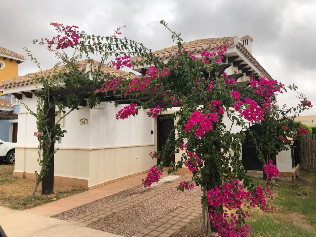Casa blanca con buganvillas rosas en la entrada
