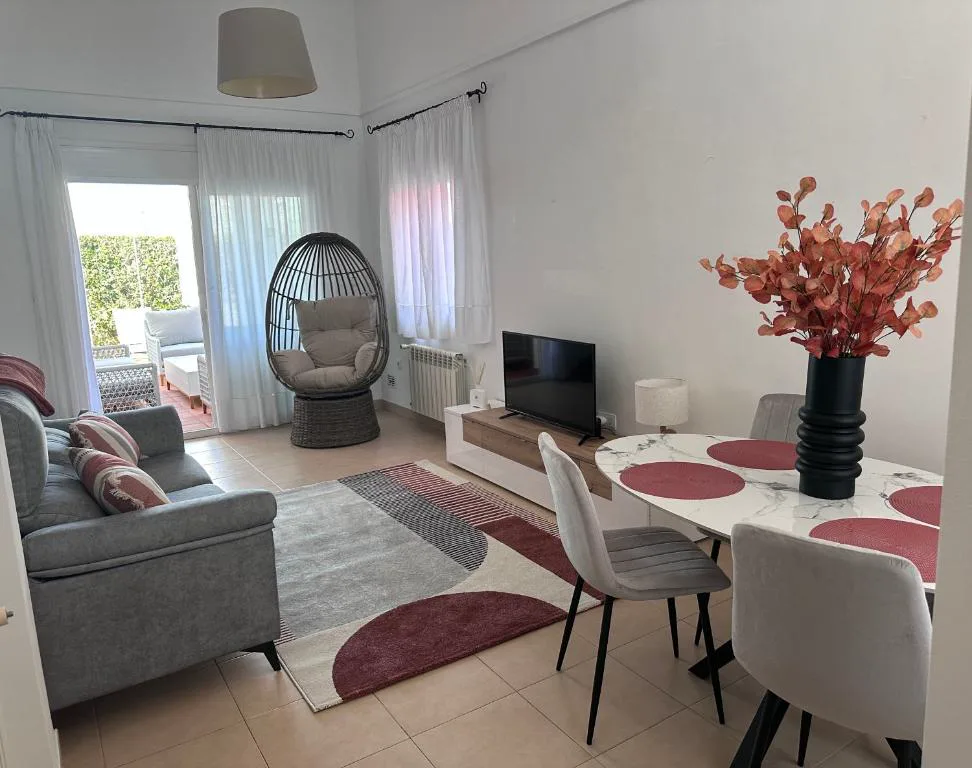 Salón con sofá gris y mesa de comedor con flores