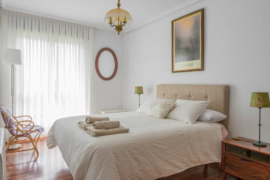 Dormitorio blanco con cama doble y lámpara