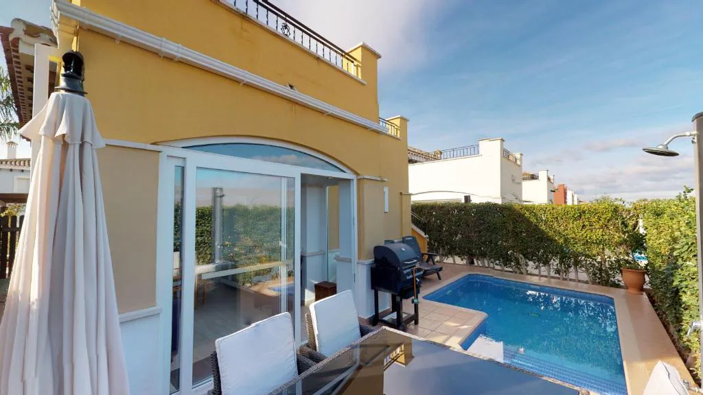 Villa amarilla con sombrilla y piscina