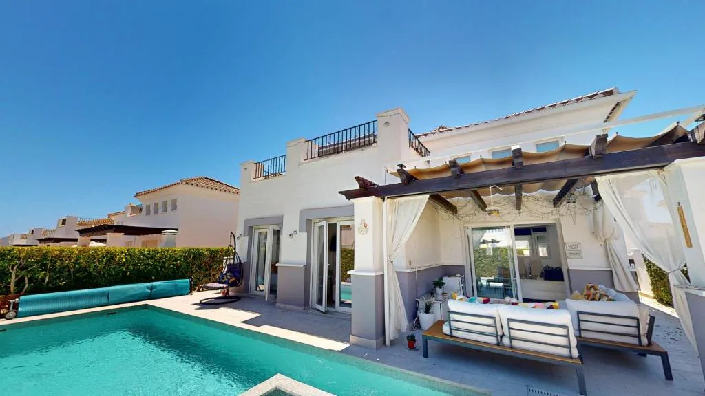 Piscina privada con tumbonas y sofás en una terraza blanca