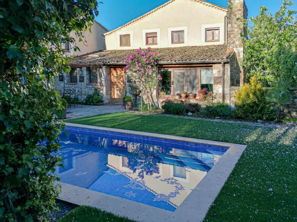 Piscina rectangular junto a la casa de piedra con pérgola