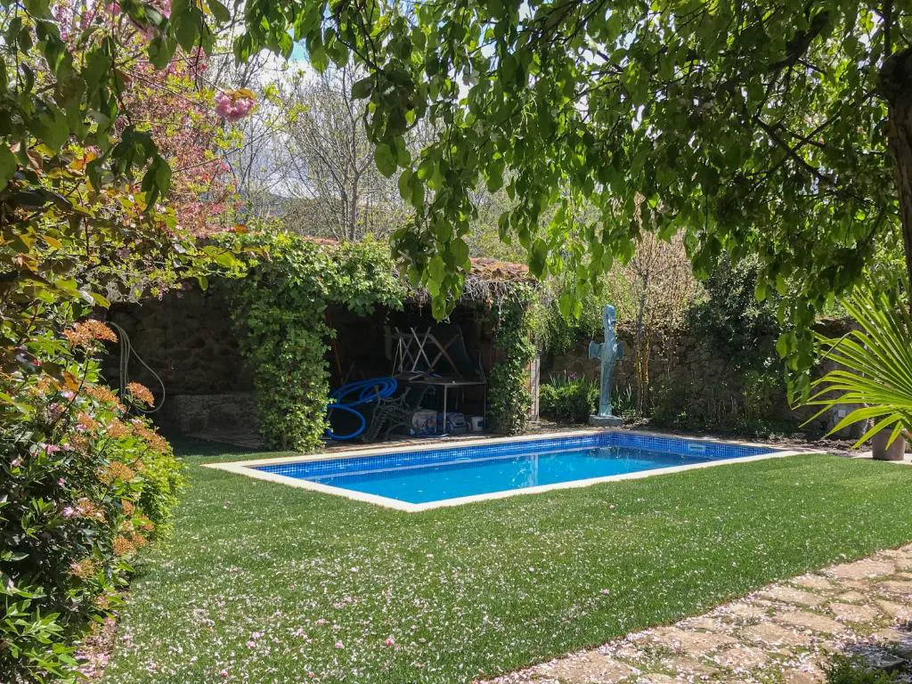 Piscina rodeada de césped y plantas floridas