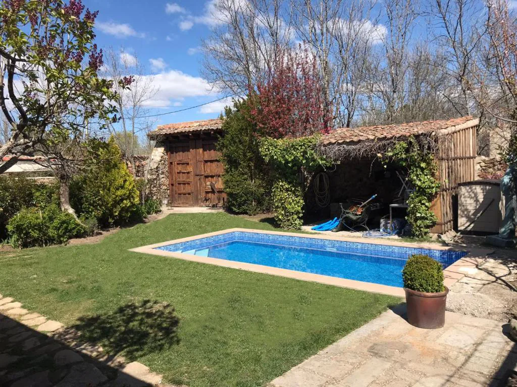 Piscina con porche de madera y jardín al fondo