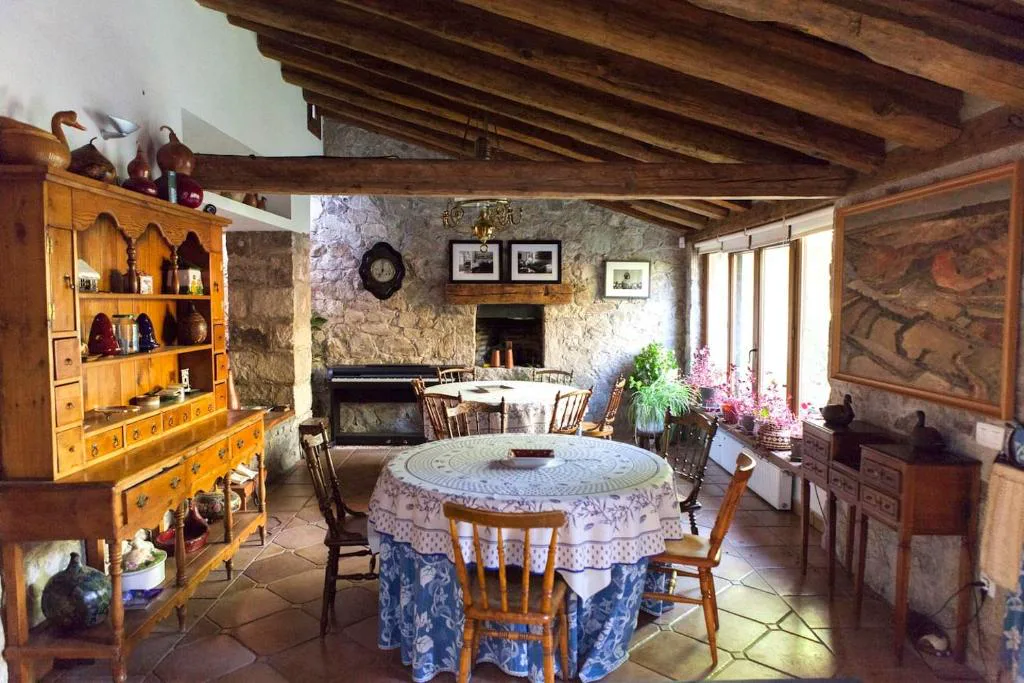 Salón rústico con chimenea, mesa redonda y vigas de madera