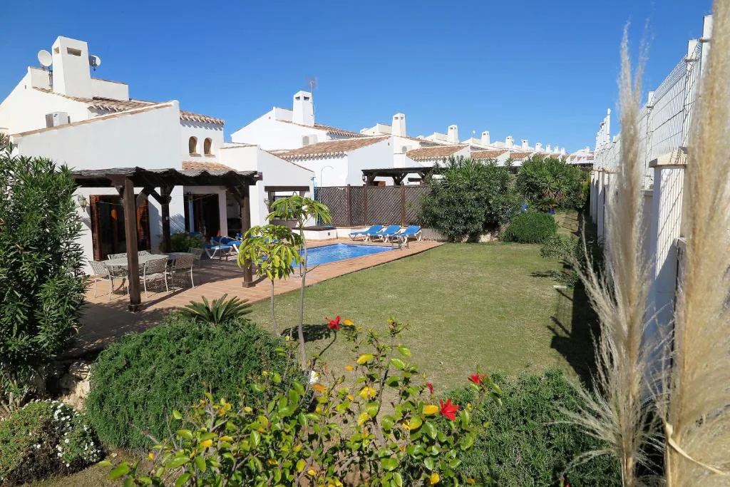 Jardín con flores y pérgola junto a la piscina