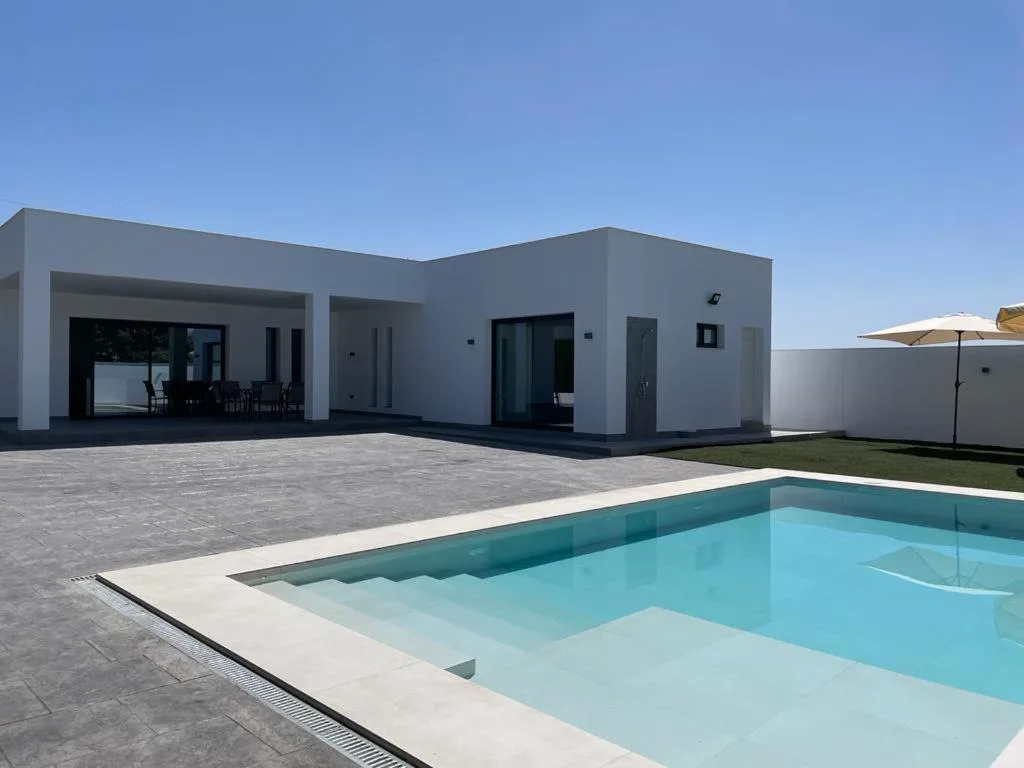 Piscina privada frente a una casa blanca moderna de una planta
