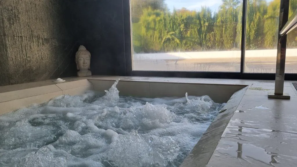 Jacuzzi interior con chorros junto a una cristalera