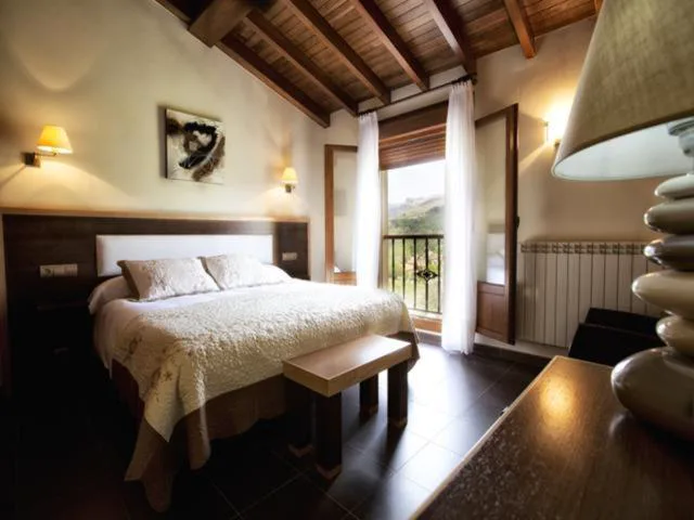 Habitación con techo de vigas de madera y balcón a las montañas, Hotel Villa de Mestas
