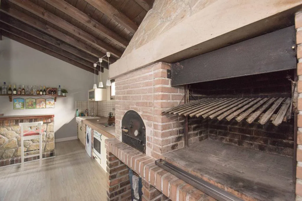 Cocina rústica con barbacoa de ladrillo y horno de leña