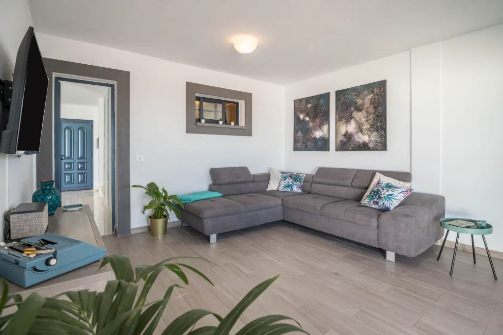Salón con sofá gris en forma de L y cuadros abstractos, Villa Esmeralda