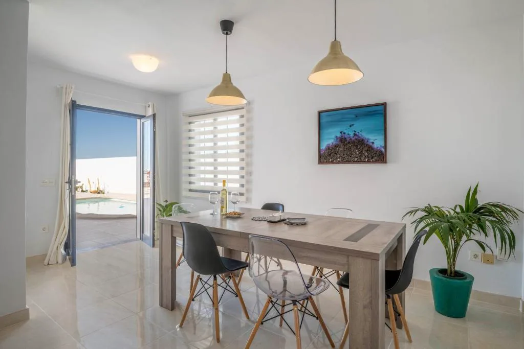 Comedor con mesa de madera y puerta abierta a la piscina, Villa Esmeralda