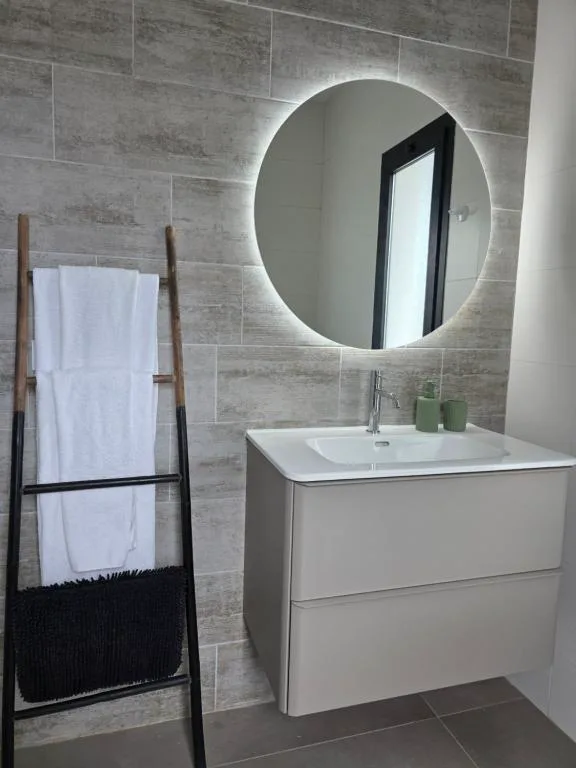 Baño moderno con espejo circular retroiluminado, Villa Montaña Colorada