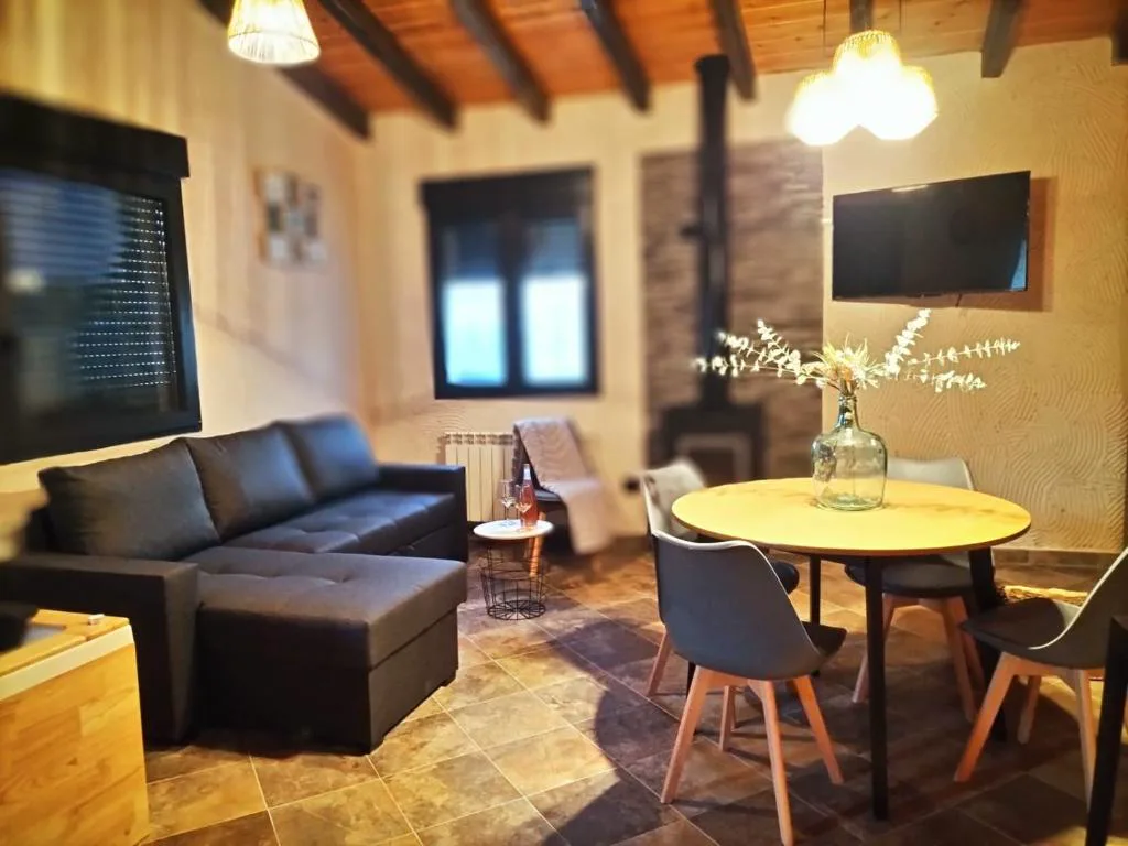 Salón con sofá negro, mesa redonda y estufa de leña