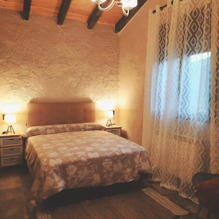 Dormitorio de luz cálida con cabecero rosado y cortina de encaje