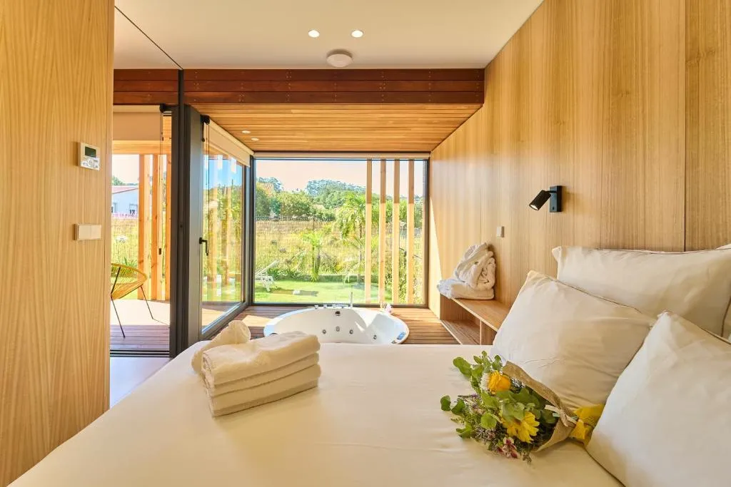 Dormitorio de la villa con bañera de hidromasaje junto al ventanal panorámico al jardín