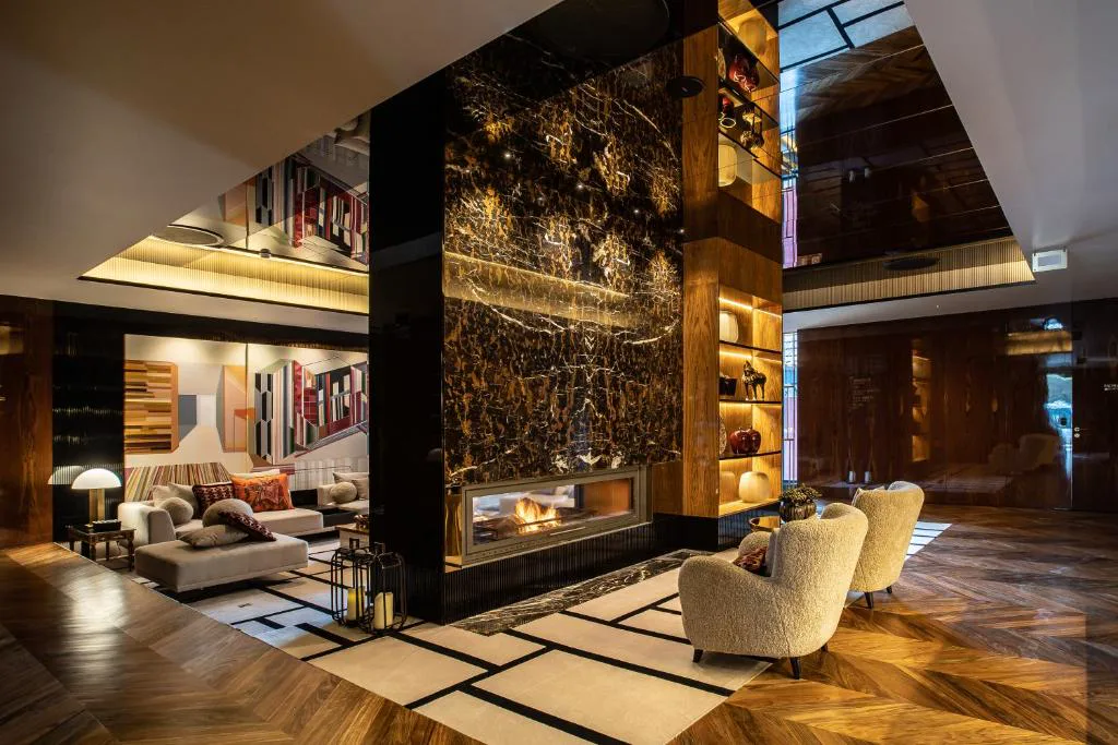 Salón con chimenea de mármol oscuro y sillones tapizados, Vinha Boutique Hotel