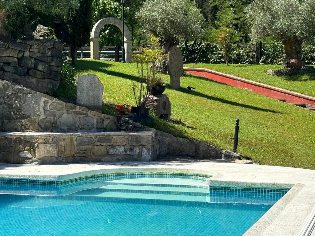 Escalones de la piscina entre jardín y muro de piedra